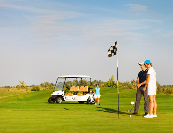 Спортивна сім'я грає в гольф на полі для гольфу
 - Фото, зображення