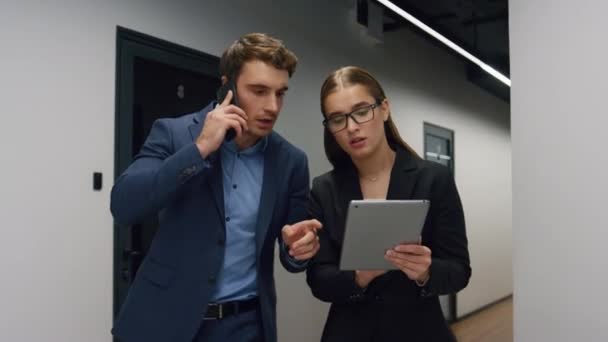 Business partners using tablet in office. Financial managers consulting client on call walking hall. Successful executive boss talk mobile phone with investor. Beautiful assistant help ceo check data - Footage, Video