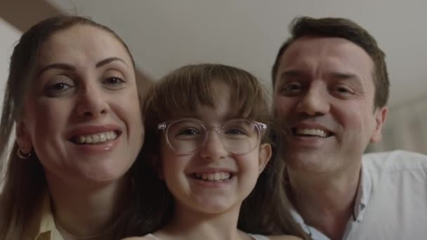 Little cute girl taking selfie with young family, recording video, photographing beautiful moment. Family looking at camera while enjoying video call. Front phone camera view. - Materiał filmowy, wideo