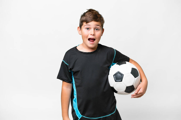 Pequeño jugador de fútbol caucásico niño sobre fondo blanco aislado con expresión facial sorpresa - Foto, Imagen