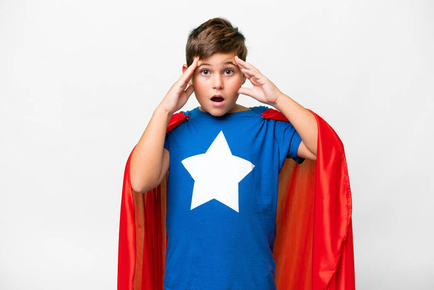 Супергеройський хлопчина над ізольованим білим фоном з несподіваним виразом - Фото, зображення