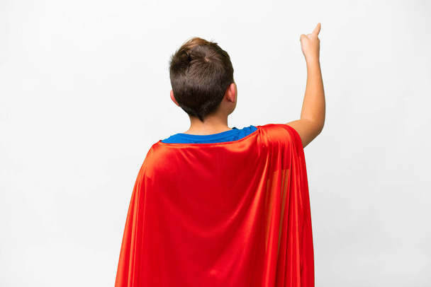 Super Hero caucasian kid over isolated white background pointing back with the index finger - Foto, Imagem