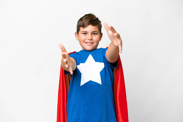 Маленький белый мальчик на изолированном белом фоне в костюме супергероя и делает предстоящий жест - Фото, изображение