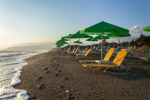 Strand lounge székek alatt zöld esernyők a tengerparton, nyaralás és pihenés koncepció, napkelte, nyári napsütéses nap, kék tiszta ég másolás tér - Fotó, kép