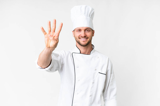 młody kaukaski kucharz na odizolowanym białym tle szczęśliwy i liczyć cztery z palcami - Zdjęcie, obraz