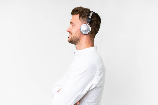 Telemarketer biały człowiek pracuje z zestawu słuchawkowego na pojedynczym białym tle w pozycji bocznej - Zdjęcie, obraz