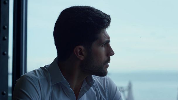 Attractive man relaxing panoramic hotel bar portrait. Thoughtful guy looking beautiful seascape waiting for business meeting in restaurant profile. Pensive male face expression closeup. - Photo, image