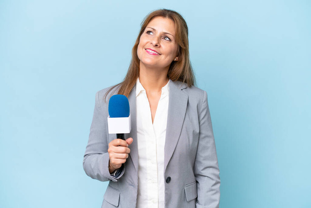 Телеведуча середнього віку жінка над ізольованим синім фоном думає про ідею під час пошуку
 - Фото, зображення