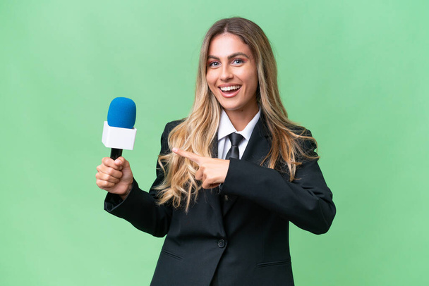 Jonge mooie Uruguayaanse tv presentator over geïsoleerde achtergrond wijzend naar de zijkant om een product te presenteren - Foto, afbeelding