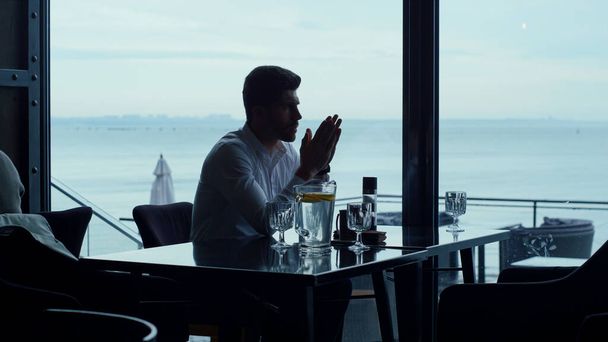 Handsome freelancer man thinking new business projects while resting panoramic restaurant. Pensive entrepreneur silhouette spending evening lunch in cafe. Worried businessman waiting partner in bar. - Foto, Imagem