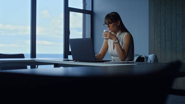 Employee holding water glass in office. Focused manager working laptop online. Brunette businesswoman hydrating searching information checking financial report. Beautiful secretary ceo look computer - Photo, Image