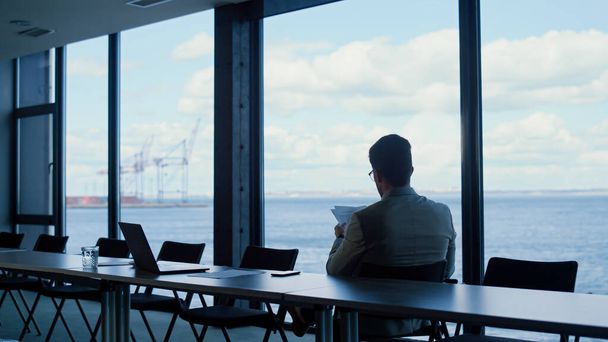 Unknown director reading papers at ocean view. Rich manager checking report at panorama window place rear view. Unrecognized businessman studying deal contract documents at luxury workplace  - Foto, Bild