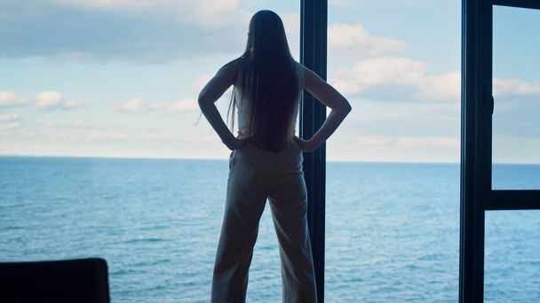 Stressed businesswoman thinking problem walking at office room panorama window. Anxious freelancer financial manager looking sea waiting for business meeting partner. Nervous worker making decision - 写真・画像