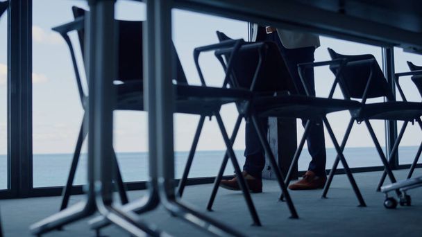Executive man legs walking alone modern company office closeup. Anonymous businessman leather shoes waiting at panoramic window dark corporate building. Unknown ceo having break alone slow motion - Foto, afbeelding