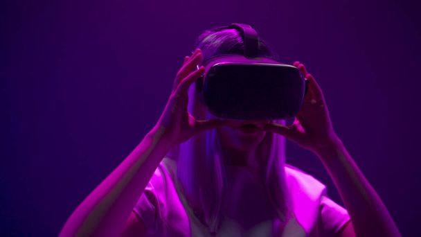 Zaimponowana kobieta zdejmuje okulary VR zbliżenie. Millennial girl podekscytowany po nowej symulacji 3D doświadczenie spowolnienia ruchu. Kobieta korzystających gier rozrywkowych kolorowy neon tło cyberpunk - Zdjęcie, obraz