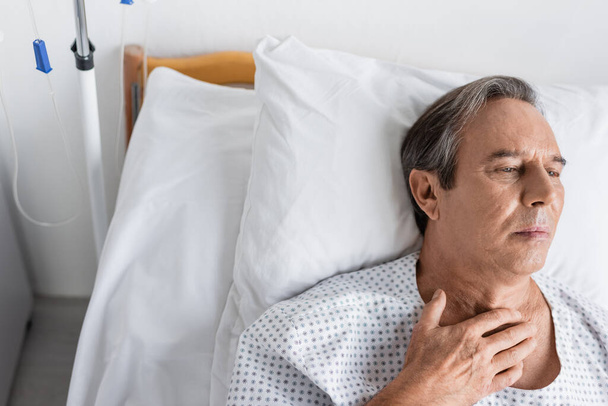 Vista ad alto angolo del paziente anziano in abito sdraiato sul letto nel reparto ospedaliero - Foto, immagini