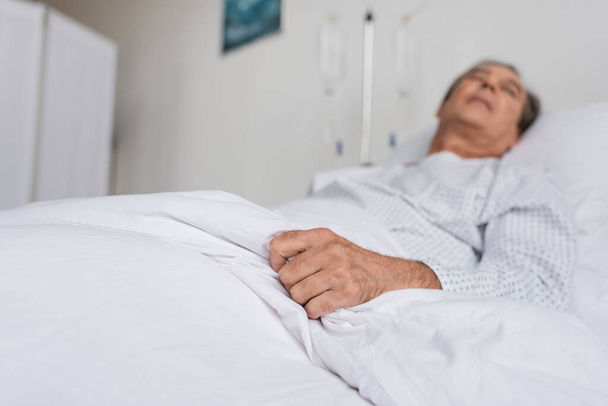 Blurred elderly patient lying on bed in hospital ward - Photo, Image