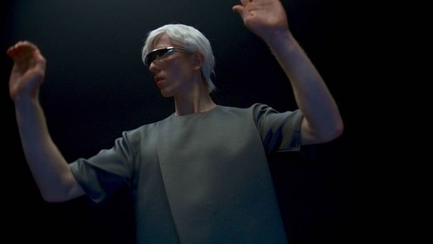 光の中でvrガラスをジェスチャー未来派の男.サイバーヘッドセットで拡張シミュレーションを没入型のミレニアル世代タッチオブジェクトに焦点を当てています。ブロンドのティーンエイジャーの男は、仮想現実ゲームをプレイ。未来の現実概念 - 写真・画像