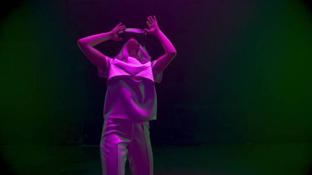 Cyber girl danst virtual reality glazen in neon lichten. Gelukkige speler genieten van augmented simulatie. Onbekende futuristische tiener onderhoudend rusten in cyberspace. Digitaal toekomsttechnologieconcept - Foto, afbeelding