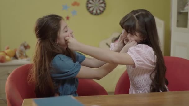 2 little girlfriends who love each other very much pinch each other's nose and cheeks in the nursery. Portrait of friends who love each other very much and have fun together. - Imágenes, Vídeo