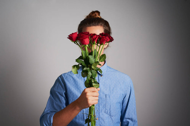 Flowers of love. Studio shot of an unrecognizable man holding flowers against a grey background - Photo, image