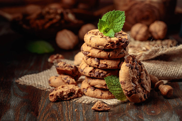 Biscoitos de chocolate recém-assados com hortelã em uma mesa de madeira com utensílios de cozinha. - Foto, Imagem