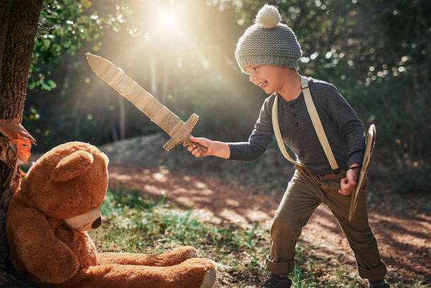 Non abbiate paura - sconfiggerò questo grande orso spaventoso. un adorabile bambino che gioca con una spada di cartone e scudo all'esterno - Foto, immagini