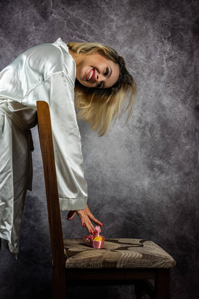 jonge slanke blonde vrouw in een stijlvolle kamerjas geïsoleerd op een prachtige achtergrond. huiskleding gezelligheid - Foto, afbeelding