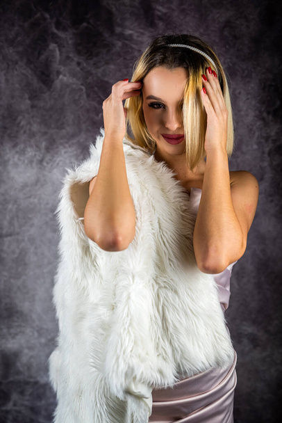 blond meisje in een jurk poseert in de studio op een gewone achtergrond. geïsoleerde Lady poseert in eco jas. Mooie luxe vrouw. Model. portret - Foto, afbeelding