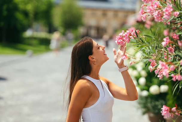 Outdoor portrait of young beautiful lady posing near flowering tree. Female beauty and fashion. City lifestyle. Copy space - Φωτογραφία, εικόνα