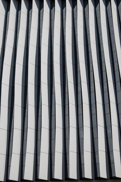Lines in architecture. Modern office facade. Fragment of tall blue building with contrast shadows. Abstract built structure background. Business quarter in a modern city. Urban scene pattern, texture. - Photo, image