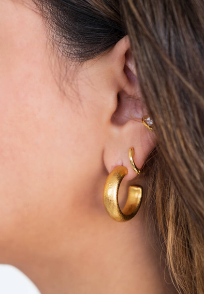 Cercle d'or gras et autres boucles d'oreilles sur l'oreille d'une femme. Un beau cadeau de Saint-Valentin. - Photo, image