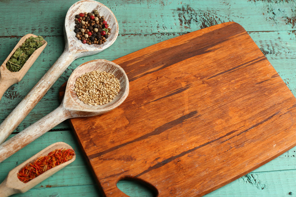 Different spices and herbs with cutting board on color wooden table background - Foto, imagen