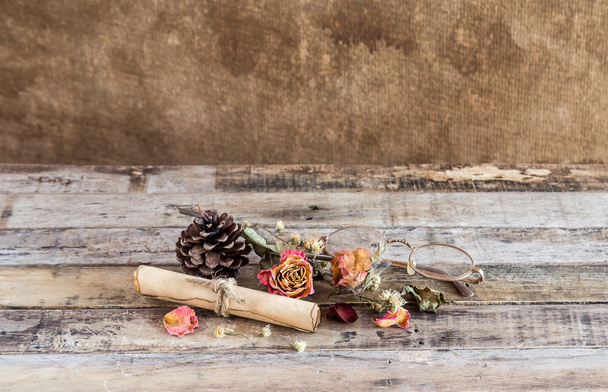 Old paper roll, glasses,and dry rose on wooden background - Foto, Imagem