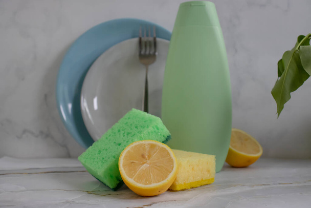 Bouteille de détergent vaisselle, citron, éponge sur fond clair - Photo, image