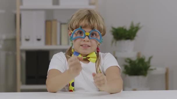Vtipná sedmiletá dívka oblečená v klaunských brýlích, motýlech a kšandách. Vysoce kvalitní 4K záběry - Záběry, video