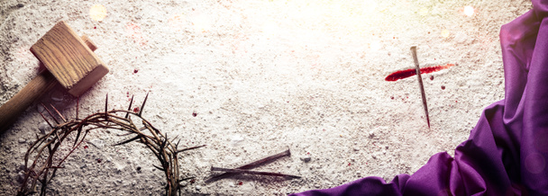 Kreuz mit Blut und Nagel auf losem Schmutzboden mit Dornenkrone, Hammer und lila Robe - Die Kreuzigung Jesu Christi - Foto, Bild