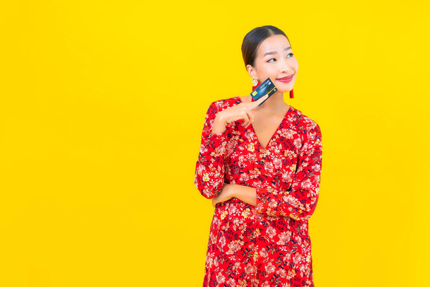 Portré gyönyörű fiatal ázsiai nő hitelkártya vásárlás sárga elszigetelt háttér - Fotó, kép