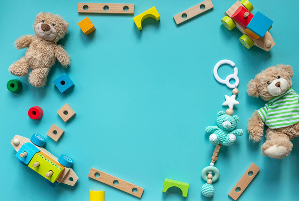 Ведмедик Тедді, дерев'яні іграшки, блоки для дітей дошкільного віку на синьому фоні. Іграшки для дитячого садка, дошкільного або денного догляду. Копіювати простір для тексту. Вид зверху, крупним планом
 - Фото, зображення