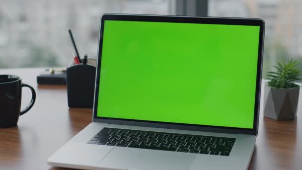 Moderní zelený monitor notebook stojící na kancelářském dřevěném stole. Pohled na počítač s klíčem chroma na stole s hrníčky na kávu. Zapnuto na zeleném displeji zápisník monitoru připraven k práci. - Záběry, video
