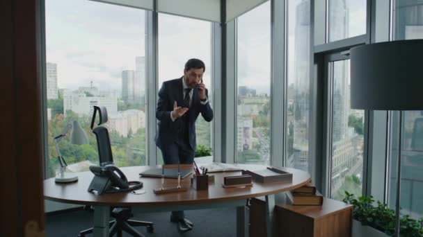 Vihainen liikemies lopettaa puhelun seisoo modernissa toimistossa. Keski-ikäinen hermostunut yrittäjä huutaa älypuhelimella. Tyytymätön liikemies reagoi tunteellisesti työn epäonnistumiseen. Yrityskriisi. - Materiaali, video