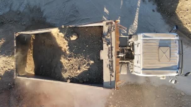 Dump truck laadt zand in graafmachine bereik op bouwplaats, luchtfoto vrachtwagen giet zand, zand wordt geloosd voor verwerking, drone view - Video