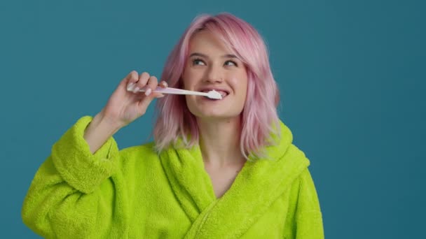 Detailní záběr hlavy mladá šťastná fena s růžové vlasy kartáčování zubů s kartáčkem a zubní pastou. Usmívající se krásná dívka těší ráno ústní anti dutiny hygienické rutiny sám v koupelně 4K - Záběry, video