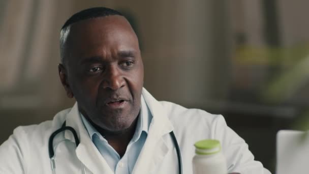 男性医師成熟アフリカ系アメリカ人男性介護者医療看護師薬錠付きボトルを保持鎮痛薬抗生物質薬免疫用サプリメントは、健康薬療法を与える - 映像、動画