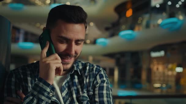 Fiatal üzletember diák etnikai spanyol arab férfi vásárló sikeres férfi ügyfél beszélni telefon vezeték nélküli mobil kapcsolat bevásárlóközpont hívás barátja megrendelés üzleti hívás csevegés mobiltelefon - Felvétel, videó