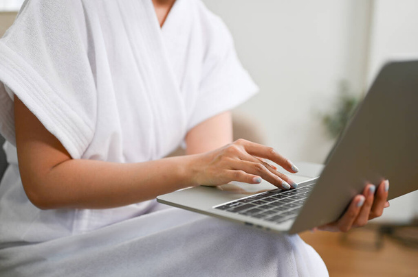 обрізані зображення, жінка в халаті з використанням ноутбука, введення на клавіатурі, робота з дому
. - Фото, зображення