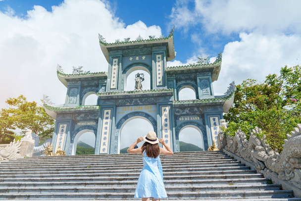 Mujer viajera visitando el templo de la pagoda Linh Ung, traducción del carácter chino. Turista con vestido azul y sombrero viajando por la ciudad de Da Nang. Vietnam y el sudeste asiático concepto de viaje - Foto, imagen