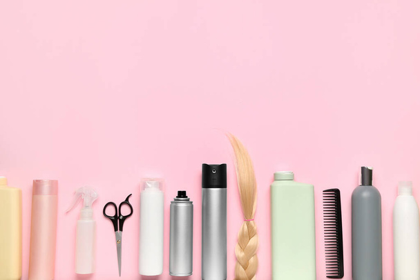 Προϊόντα περιποίησης μαλλιών με ψαλίδι και πλεγμένο σκέλος σε ροζ φόντο - Φωτογραφία, εικόνα