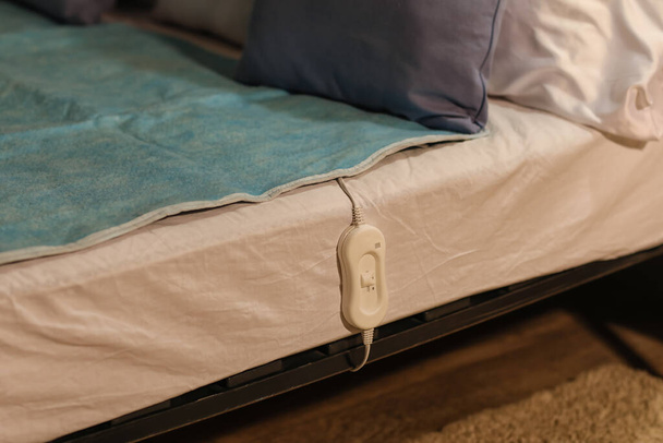 Coussin chauffant électrique avec contrôleur au lit la nuit, gros plan - Photo, image