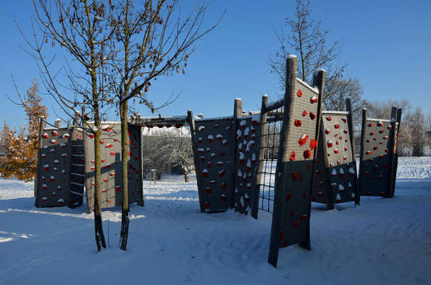 mur d'escalade sur l'aire de jeux dans le parc. poutres pleines avec poignées d'escalade en forme de pierres colorées en matériau composite pour bloc, surplomb, pont, tunnel, ciel bleu - Photo, image